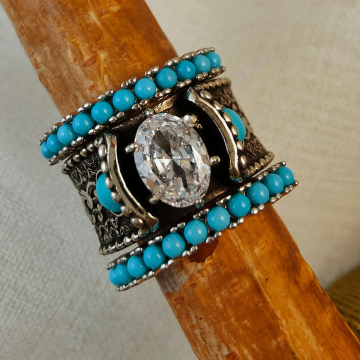 Intricate turquoise and diamond ring with wave engraving on wooden background