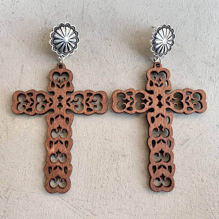 Intricate hollow leather cross earrings with silver accents and blue stones.