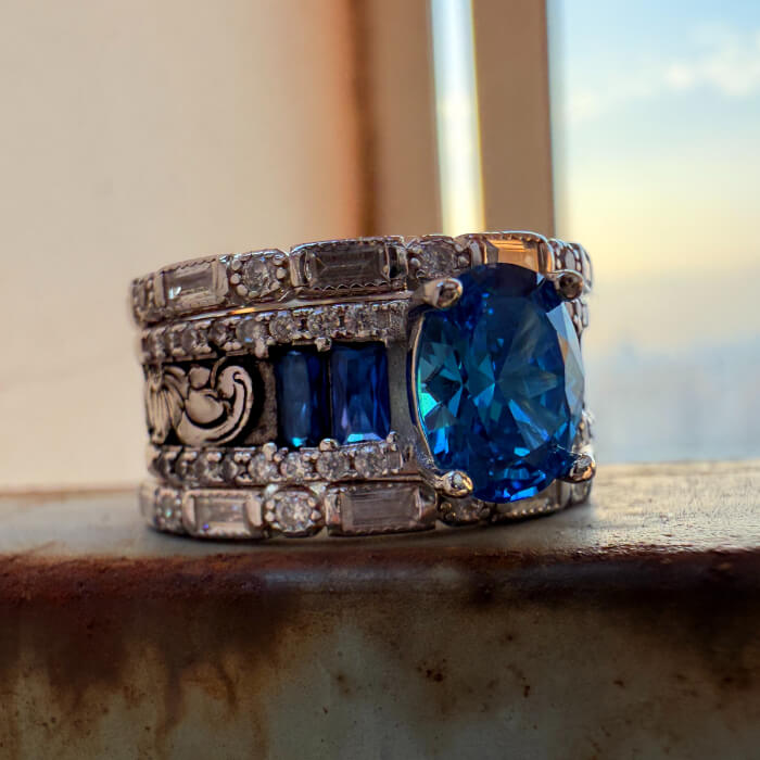 Detailed vintage sapphire diamond engagement ring with blue stones on rustic surface