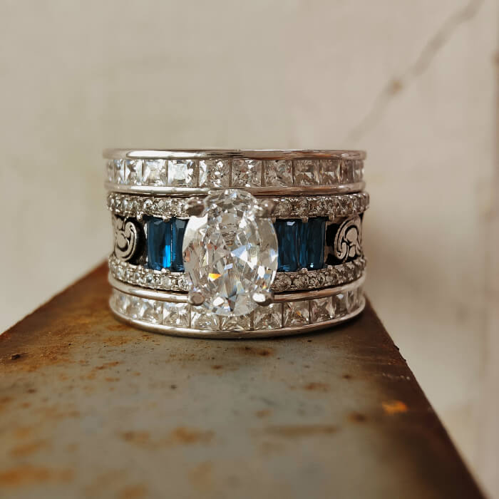 Wide band engagement ring with oval diamond and sapphire accents
