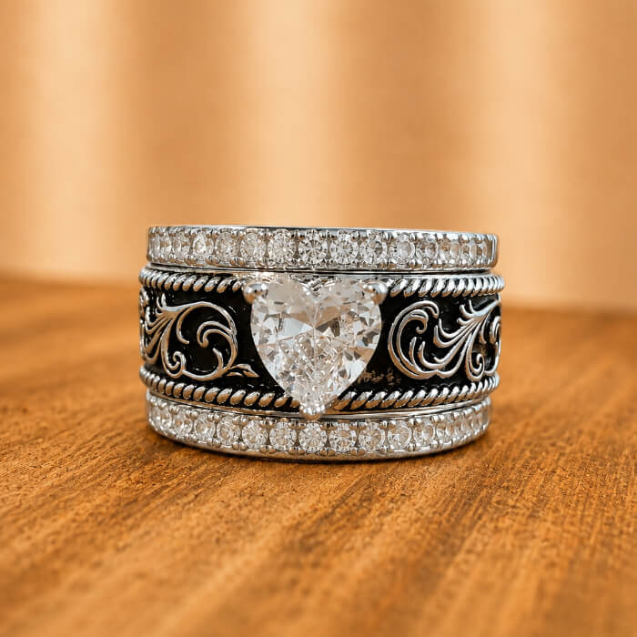 Front view of three-piece western wedding ring set with heart-shaped clear center and black scroll engraving
