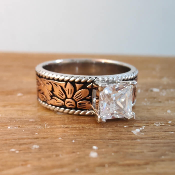 Close-up of rose gold flower engraved engagement ring with diamond accent