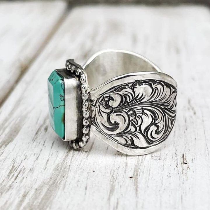 Rectangular turquoise ring with ornate floral design in polished silver