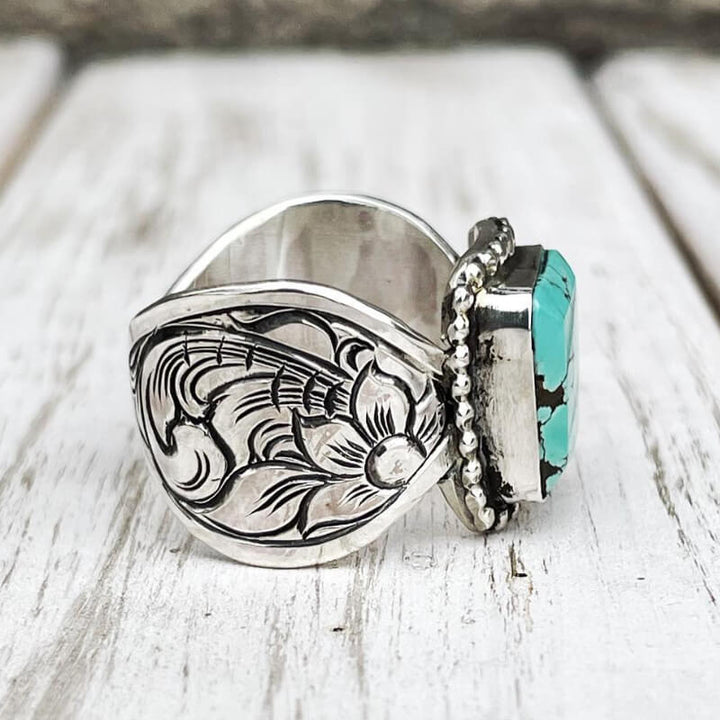 Intricately engraved silver band featuring rectangular turquoise stone
