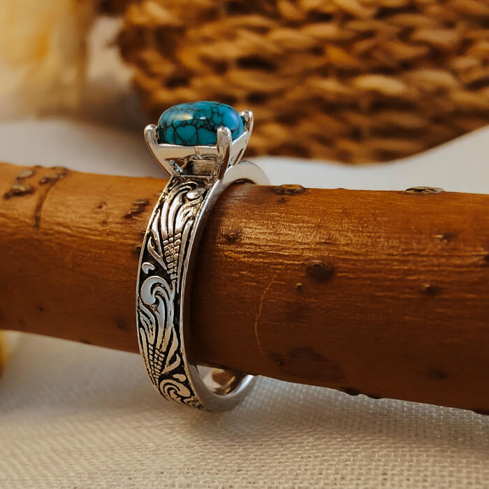 Silver flower engraved ring with turquoise stone, showcasing Western jewelry style.