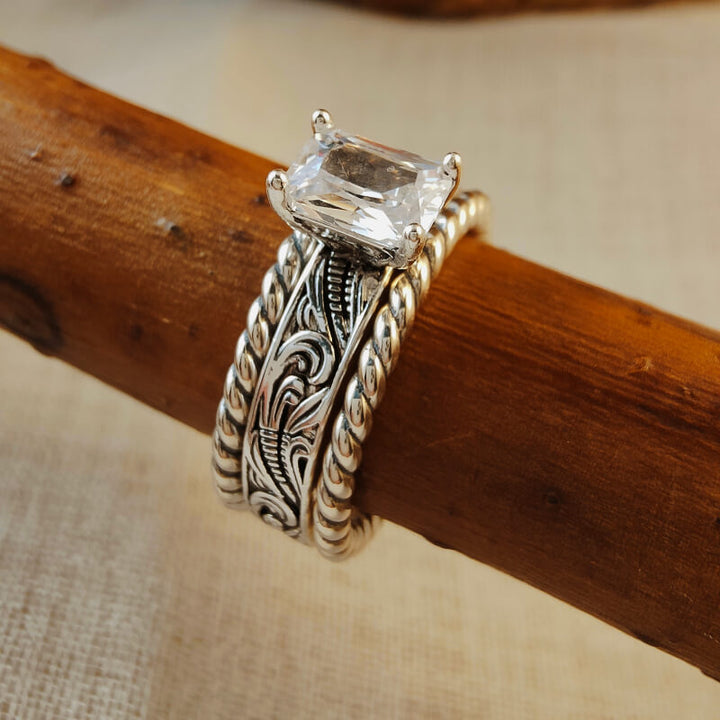 Silver twist band ring with large rectangular zircon on wood background.