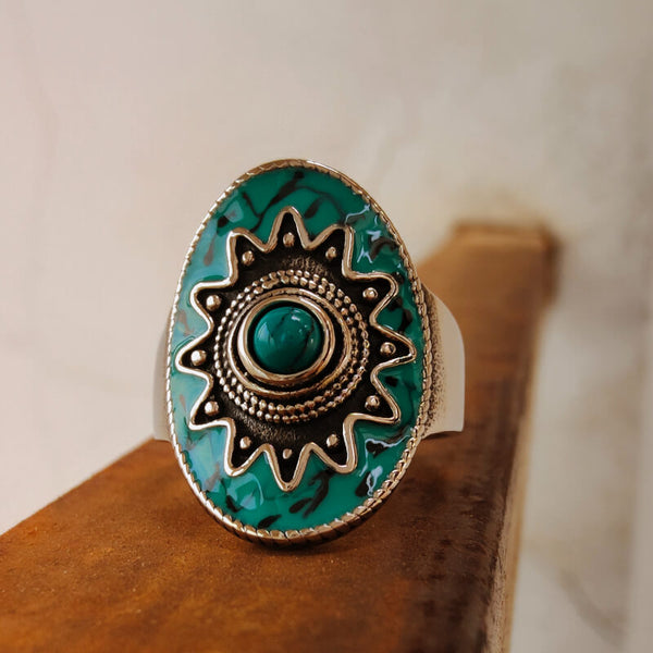 Turquoise ring featuring a round green stone and decorative silver setting.