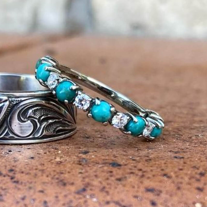 Silver band ring with round turquoise and diamond stones on rustic background.