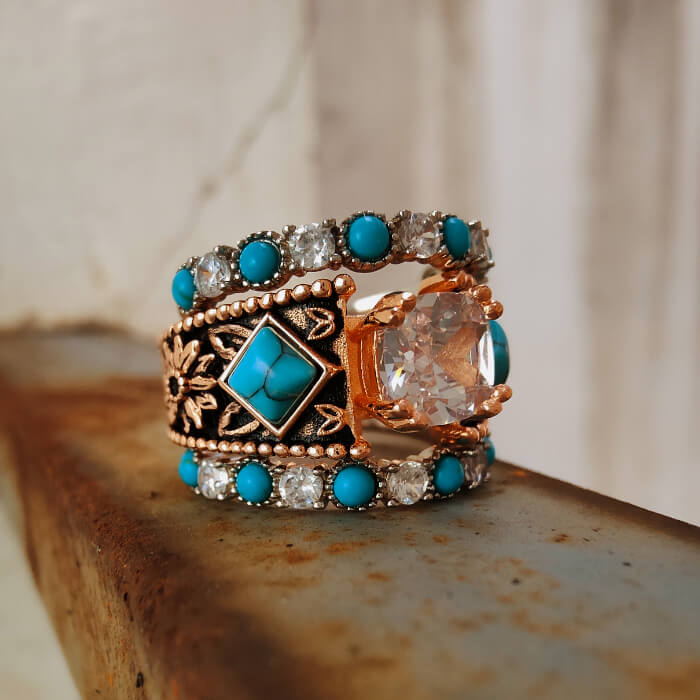 Rose gold ring with turquoise stones and a large center gem, showcasing Western design.