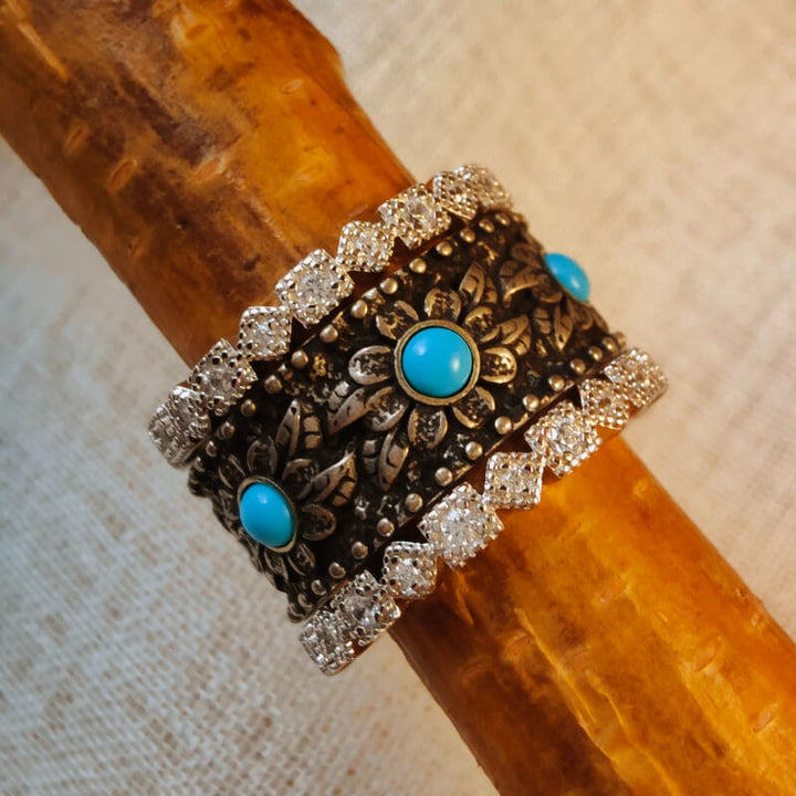 Turquoise flower stackable ring with zircon accents on a wooden background.