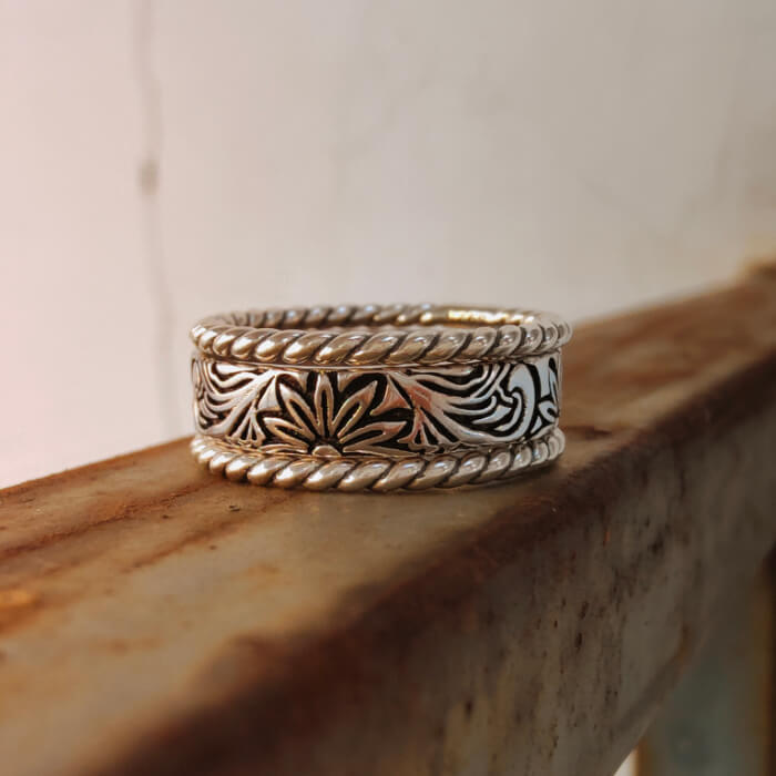 Silver band ring with detailed flower engravings and twisted border design