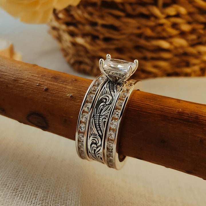 Three-piece silver engagement ring set with ornate engravings and a large zircon stone.