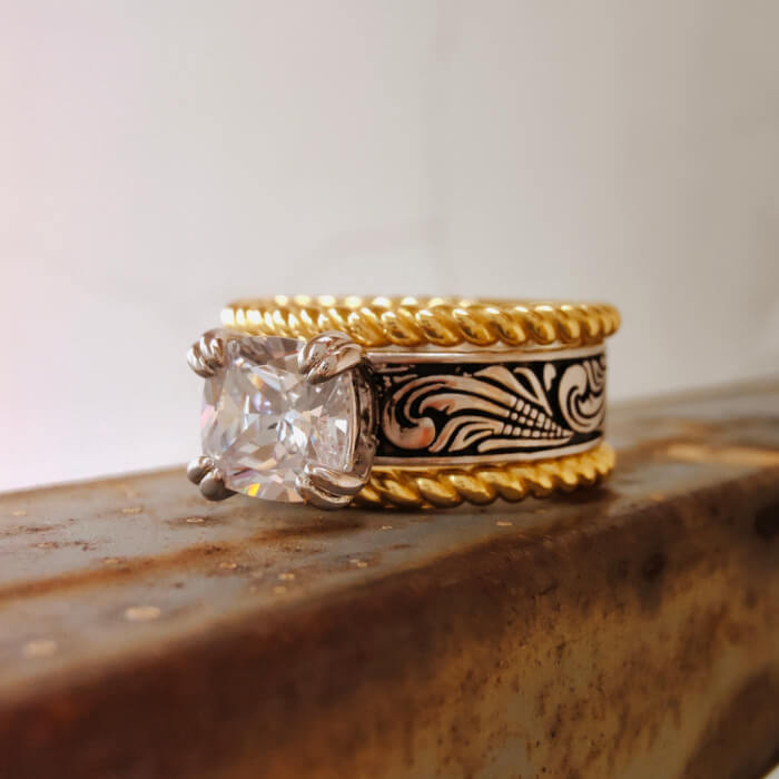 Two-tone Western-style ring featuring emerald cut zircon and floral engraving.