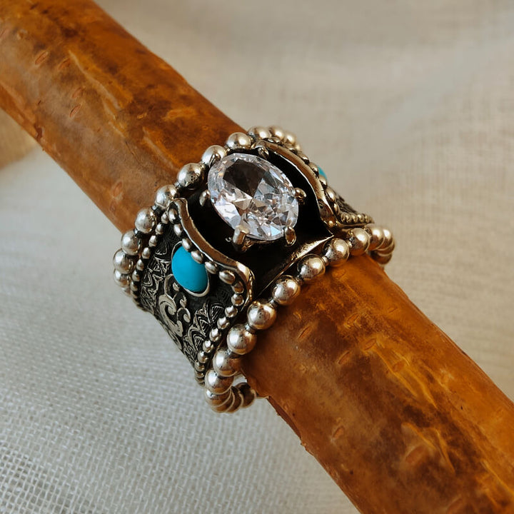 Sterling silver ring with zircon centerpiece and turquoise accents, ornate design.