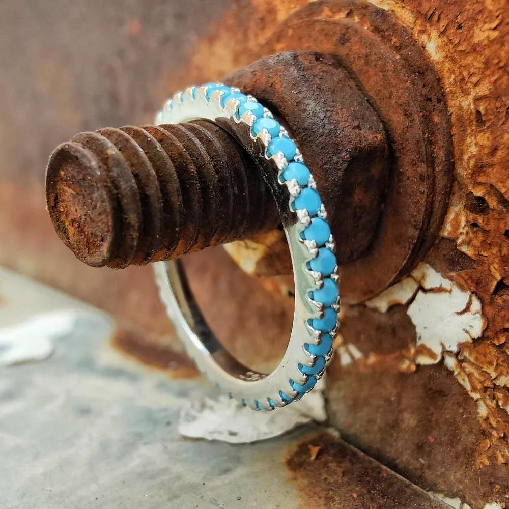 Slim turquoise stacking ring displayed around a weathered metal bolt