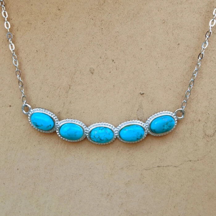 Five oval turquoise stones in a curved sterling silver bar necklace, front view