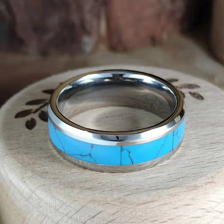 Inlaid turquoise band ring with blue inlay and sleek silver band on wood.