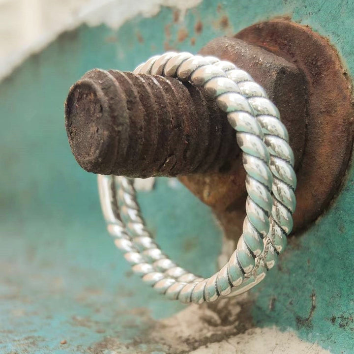 Sterling silver Western Twist Band Ring on a rusty metal bolt.