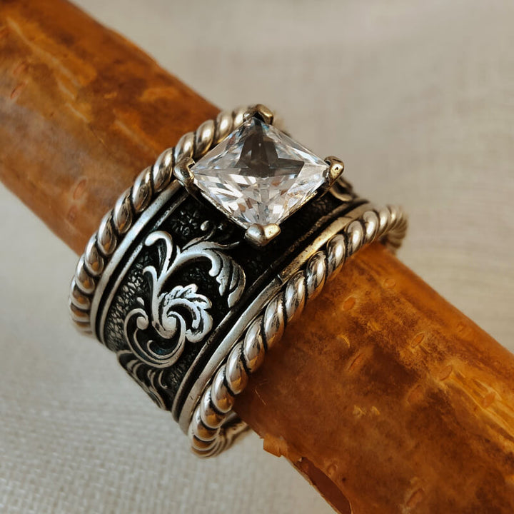 Sterling silver ring set with square zircon stone and detailed floral pattern.