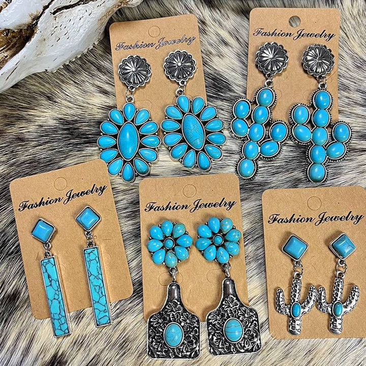 Collection of turquoise earrings on display, featuring different styles and silver accents.