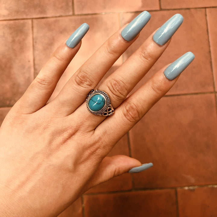 Vintage turquoise ring with intricate silver setting on a woman's hand