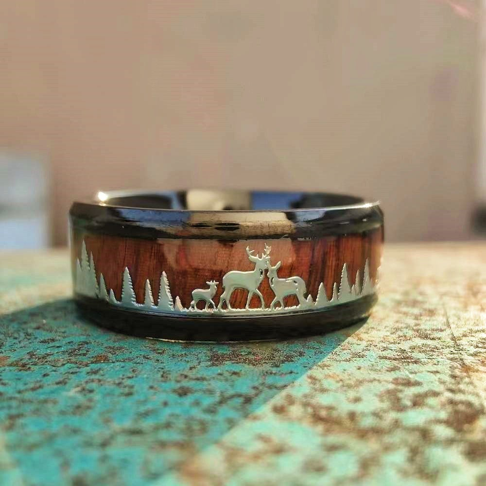Stainless steel band ring with elk and forest engravings on wooden inlay.