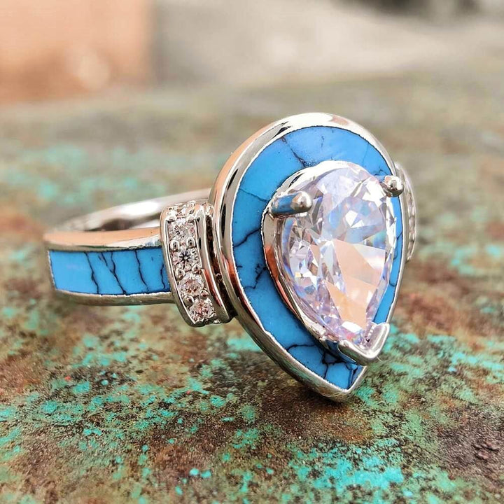 Pear-shaped zircon engagement ring with turquoise band and diamond accents