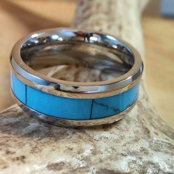 Turquoise inlaid band ring with polished silver frame on a textured background