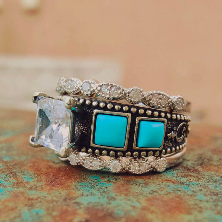 Turquoise and diamond ring set with a square zircon gem and unique band design.