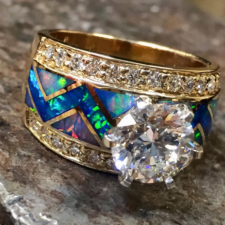 Gold band engagement ring with blue opal inlay and a round diamond centerpiece.