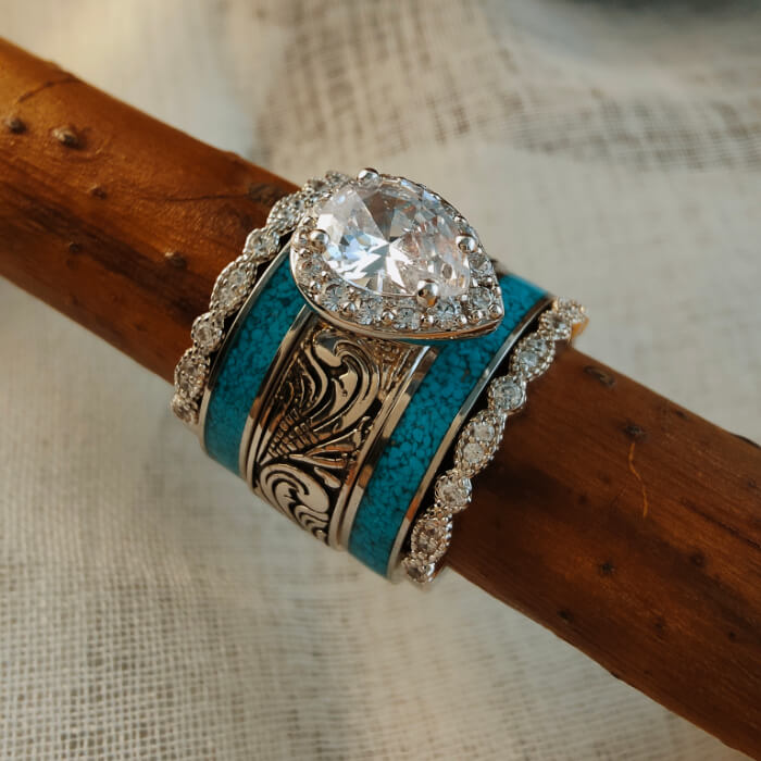 Five-piece wedding ring set with pear diamond and turquoise bands on wood