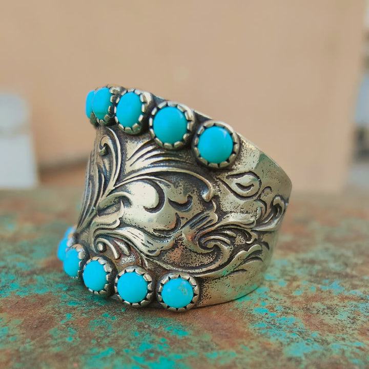 Detailed silver cuff ring with turquoise accents and ornate floral designs