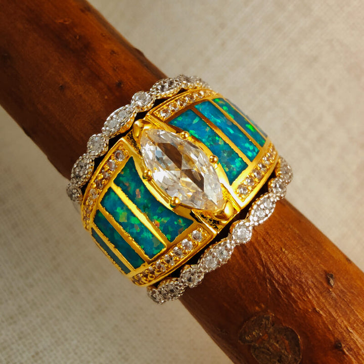 Gold engagement ring with blue opal inlay and sparkling zircon embellishments.