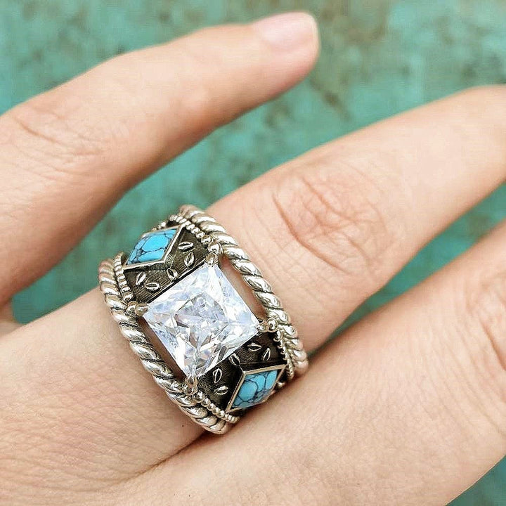 Sterling silver ring with square crystal and turquoise inlay, showcased on a hand.
