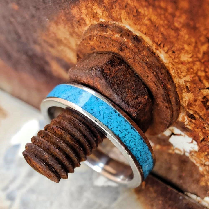 Turquoise square stacker band on a rusty metal bolt