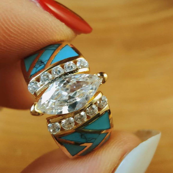 Gold ring with marquise diamond and turquoise inlay, accented by small diamonds.