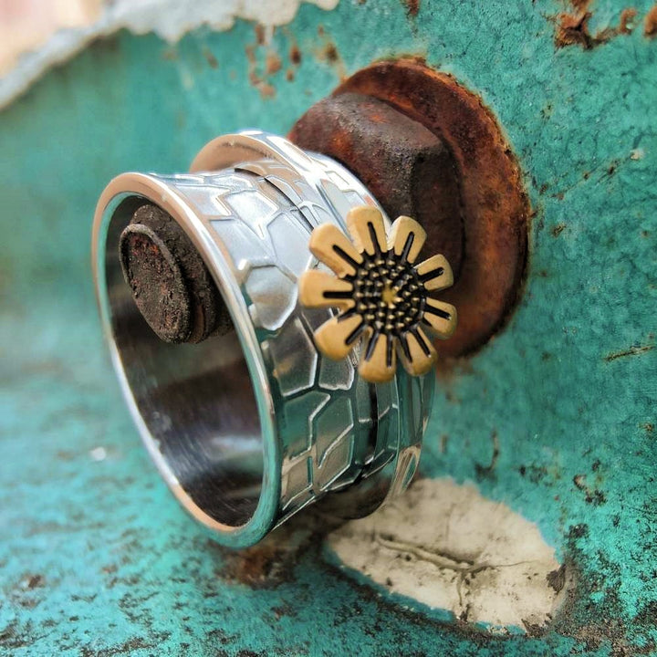 Steel band ring with rotating sunflower accent on rusty background