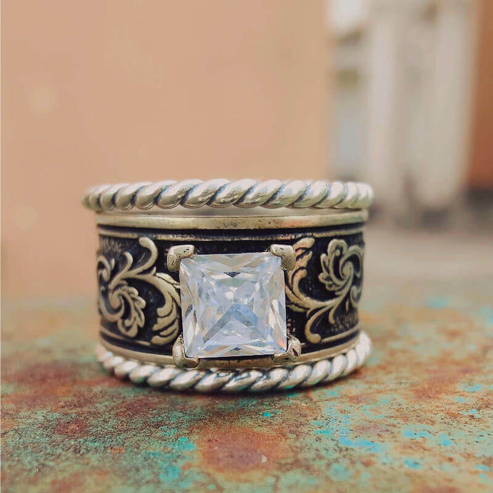 Sterling silver ring featuring a large clear zircon stone and ornate floral design.