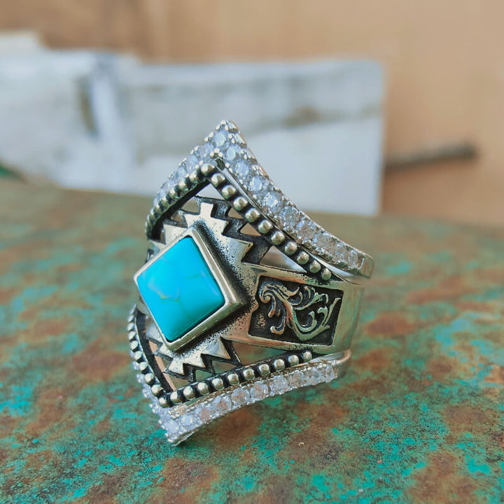 Intricate sterling silver ring featuring square turquoise stone and sparkling accents