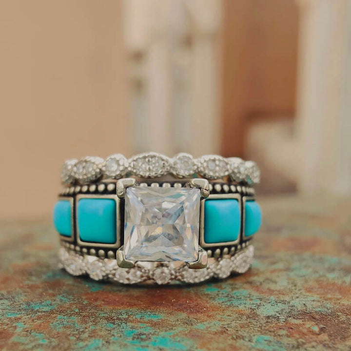 Turquoise engagement ring with diamond accents and intricate band design.