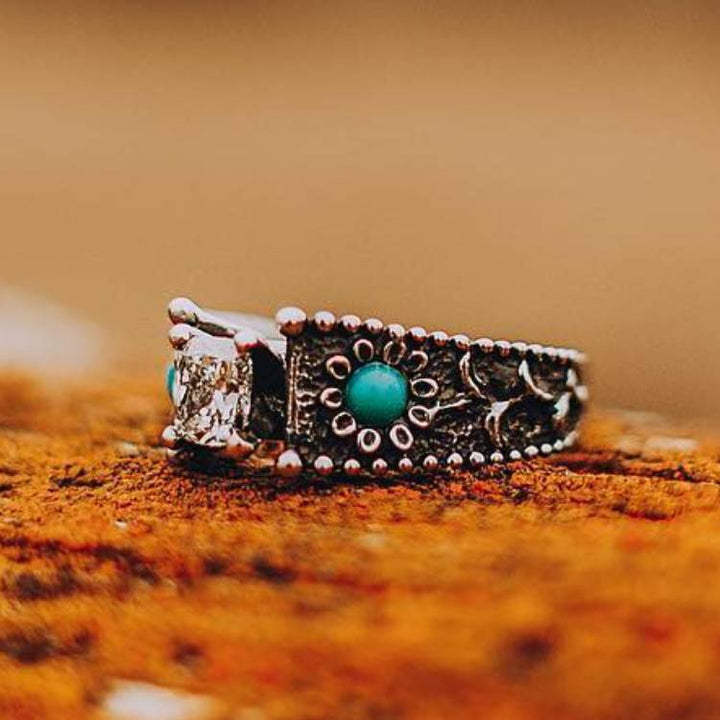 Vintage turquoise engagement ring with clear stone and floral engravings.