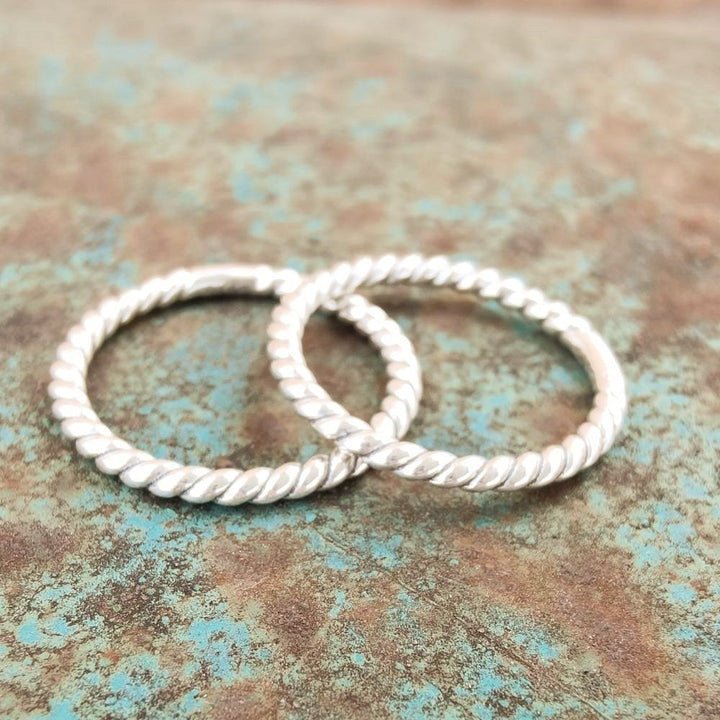 Twisted band rings made of sterling silver on a textured rustic background