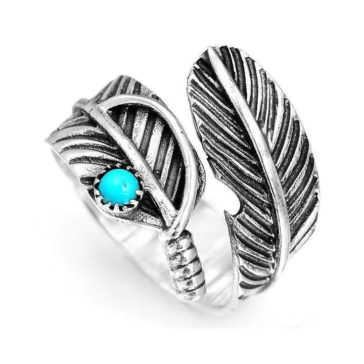 Turquoise stone ring featuring silver feather design and an elegant twist band.
