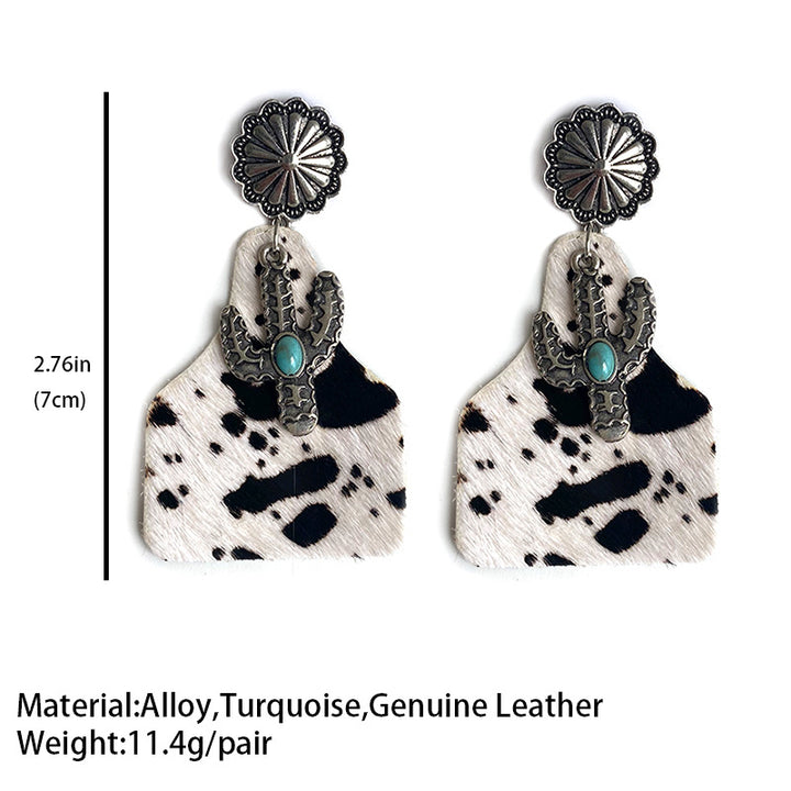 Cactus earrings with turquoise gem on cowhide print background, silver flower top.