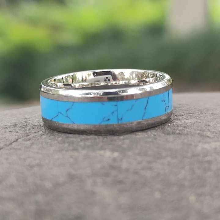 Turquoise inlaid band ring with polished silver setting against a natural background