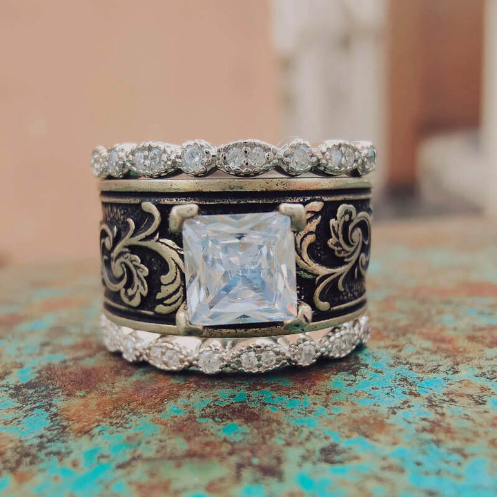 Sterling silver wedding ring set with floral engravings and central cubic zirconia.