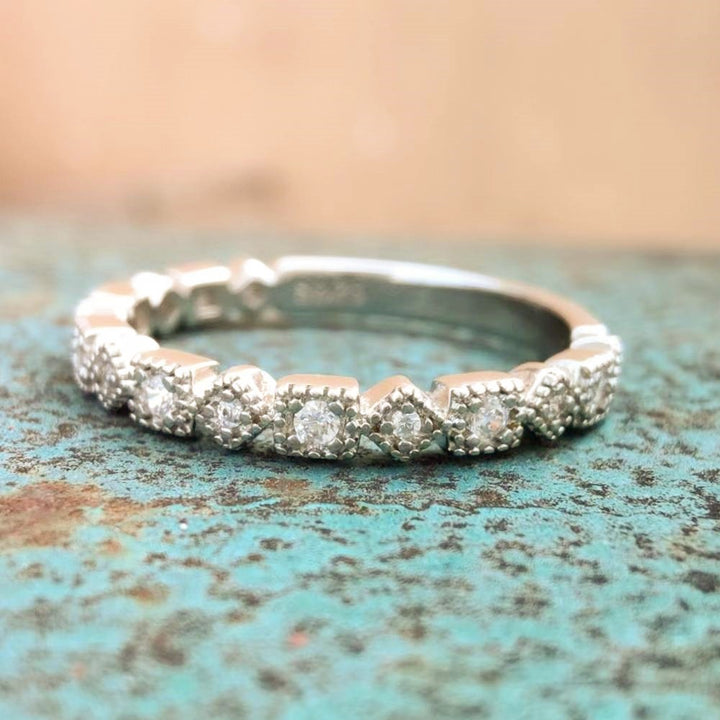 Close-up of vintage diamond band ring in polished silver with square design.