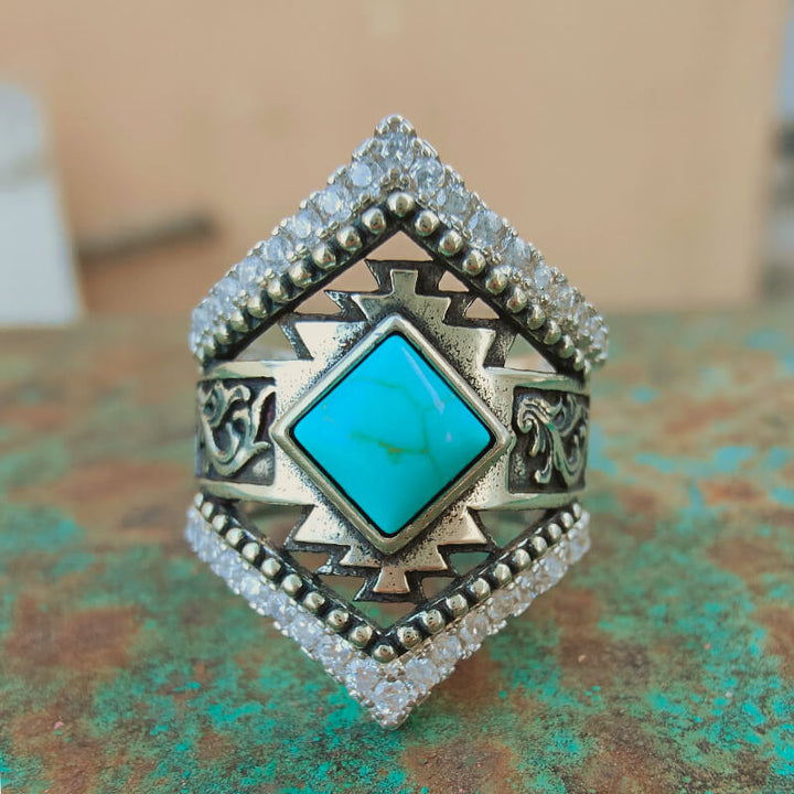 Square turquoise stone ring with ornate silver details and sparkling accents