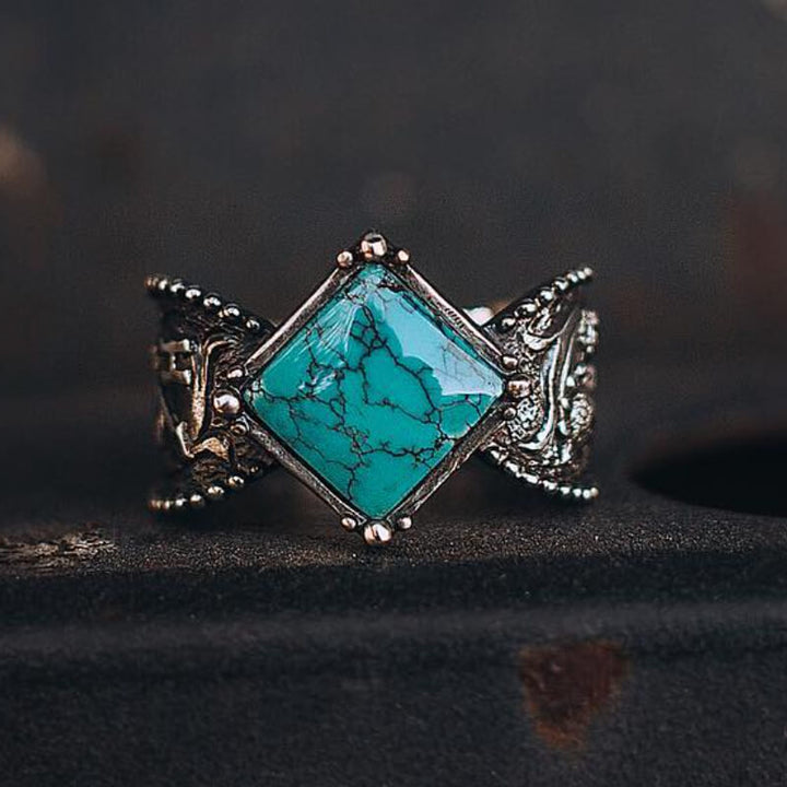 Square turquoise ring with intricate engravings and diamond shape, set in silver.
