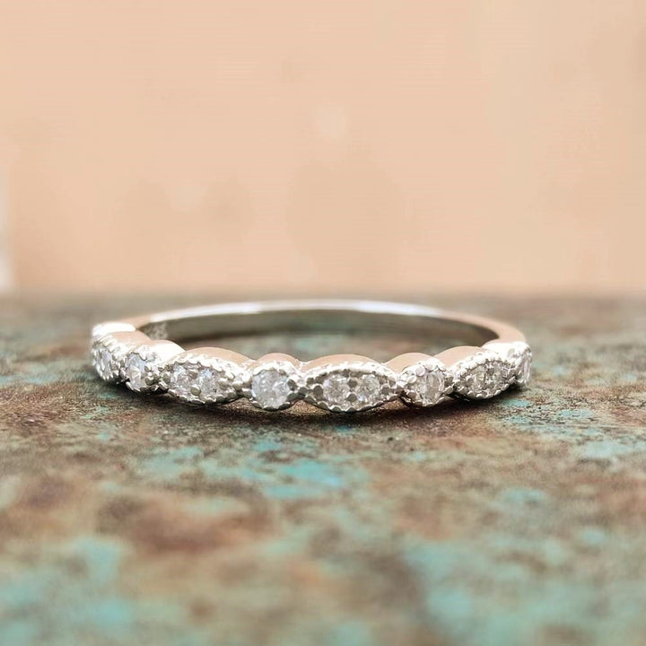 Vintage sterling silver band ring with zircon stones on textured green surface